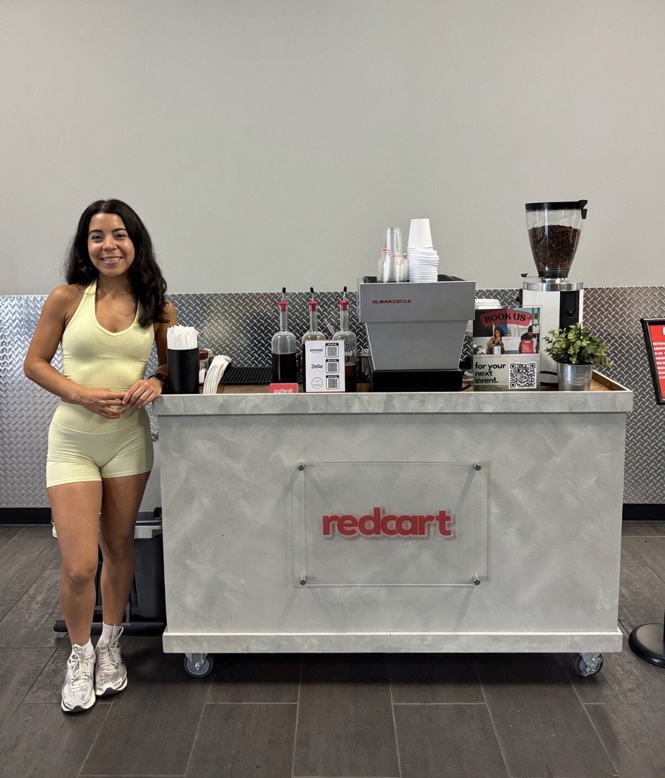 The Redcart mobile espresso cart setup with a smiling barista ready to serve
